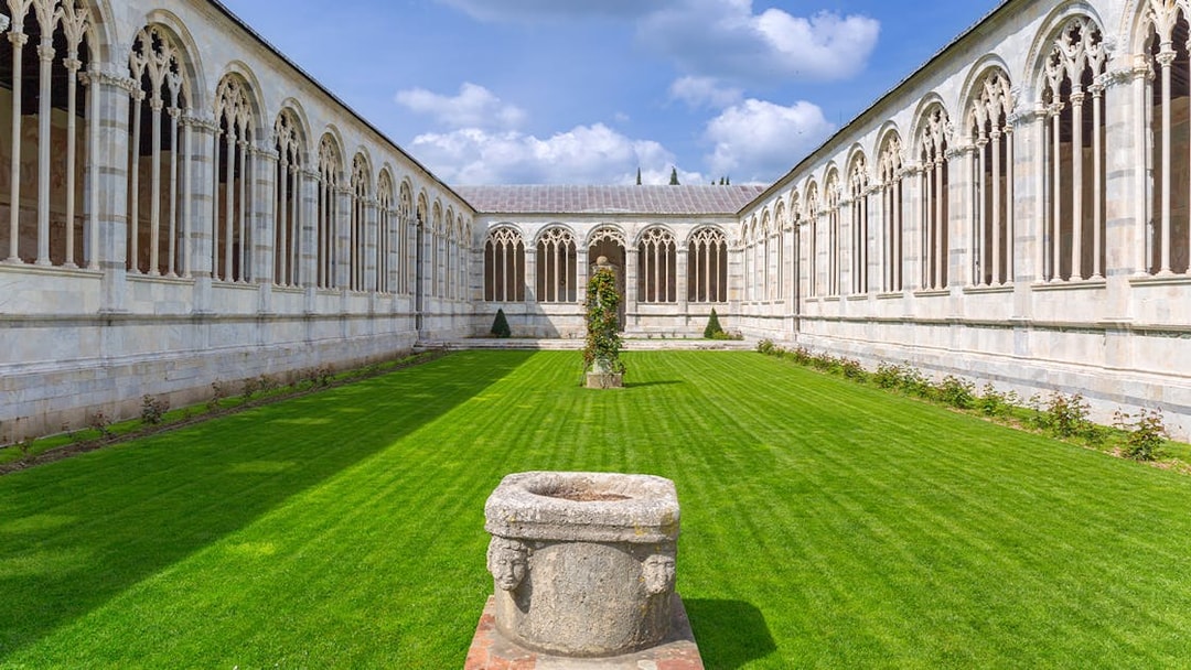 Pisa Camposanto courtyard with Gothic arches and green lawn in Pisa Cathedral Square.