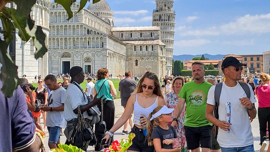 Tourists walking near Pisa Cathedral and Leaning Tower on a guided tour in Pisa, Italy.