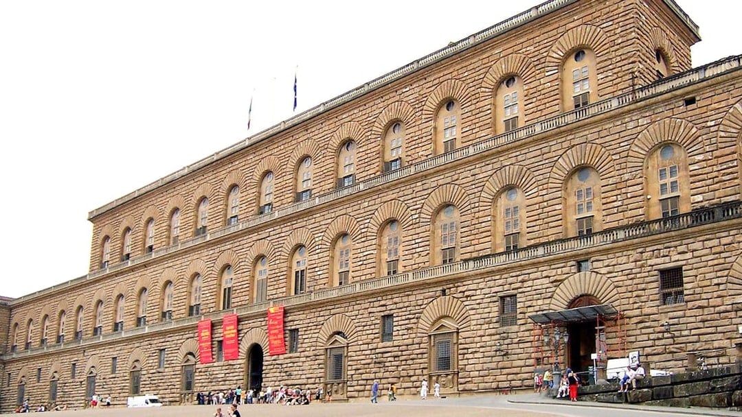 Pitti Palace facade in Florence, Italy, with visitors outside.