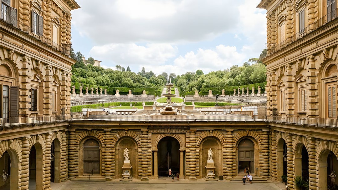 Pitti Palace courtyard with view of Boboli Garden statues and greenery, Florence, Italy.