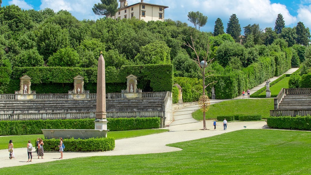 Visitors exploring Boboli Gardens with statues and obelisk, Florence.