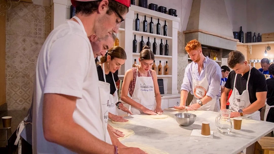 Participants making pizza dough in a cooking class, Italy.