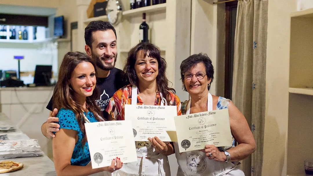 Participants holding certificates after a pizza and gelato making class in Florence.
