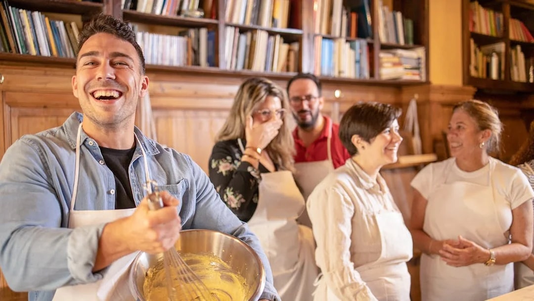 Group enjoying a pizza making class in Florence, mixing ingredients in a cozy kitchen setting.