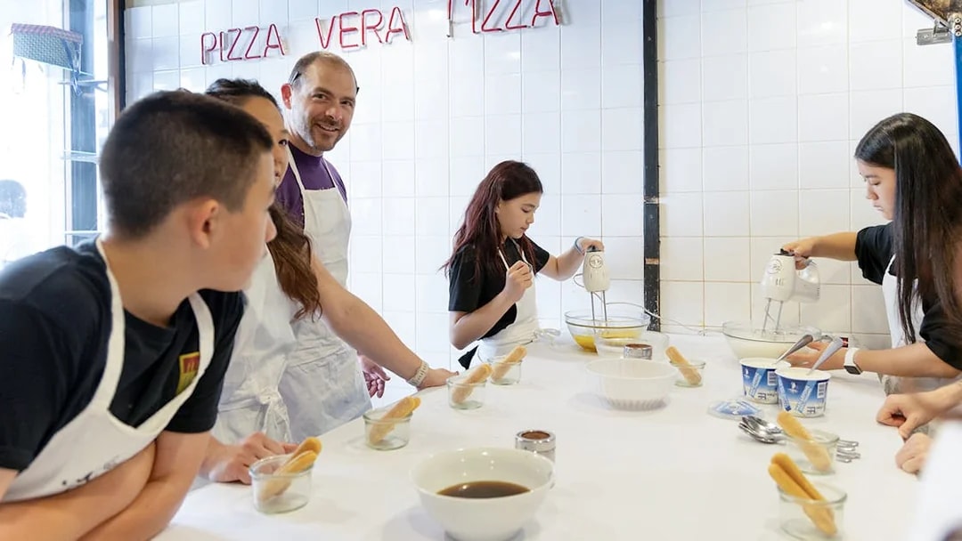 Participants making tiramisu in a Rome cooking class kitchen.