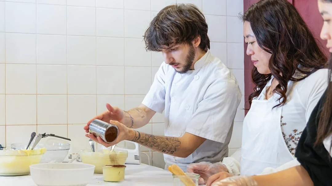 Participants making tiramisu in a Rome cooking class kitchen.