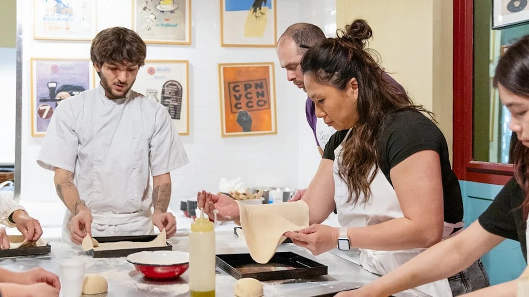 Participants making pizza dough in a Rome kitchen cooking class.