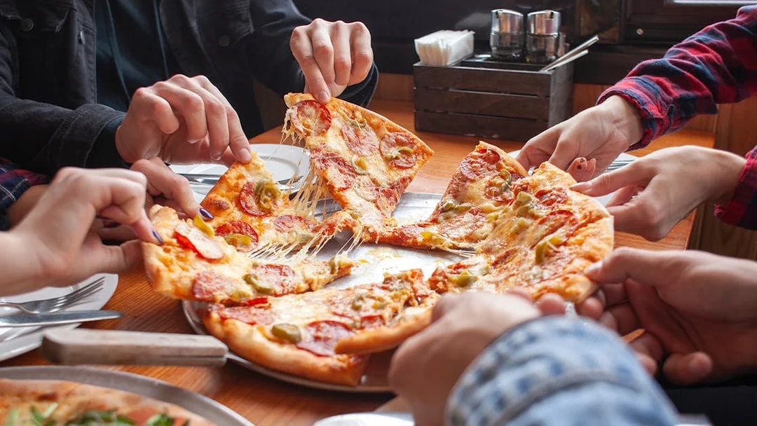 Group sharing pizza at a restaurant in Milano Bovisa.