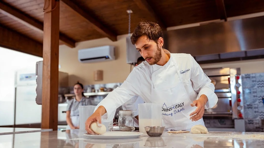 Chef preparing dough in a Palermo cooking class kitchen.