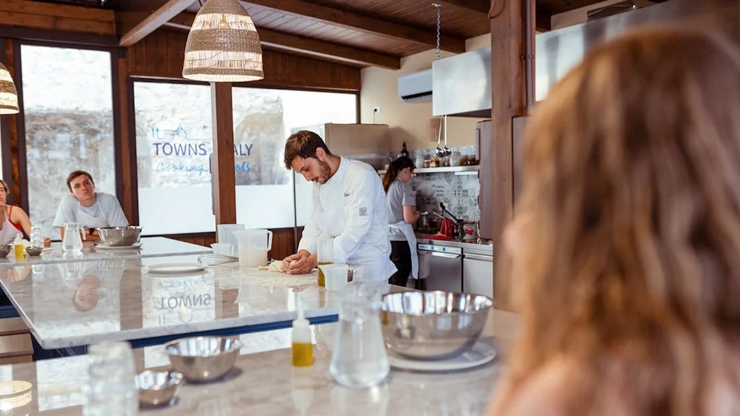 Chef kneading dough during a cooking class in Palermo kitchen.
