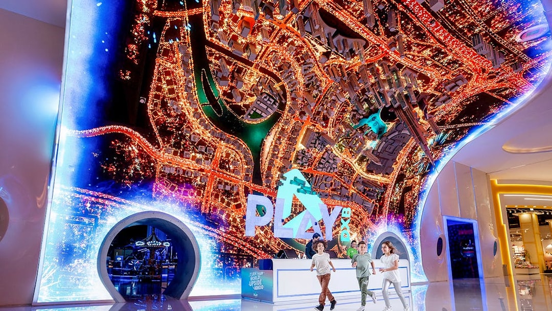 Play DXB entrance with children running, featuring a vibrant cityscape display.