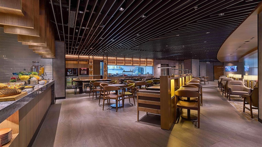 Plaza Premium First lounge seating area with dining tables and buffet counter at Satellite Terminal.