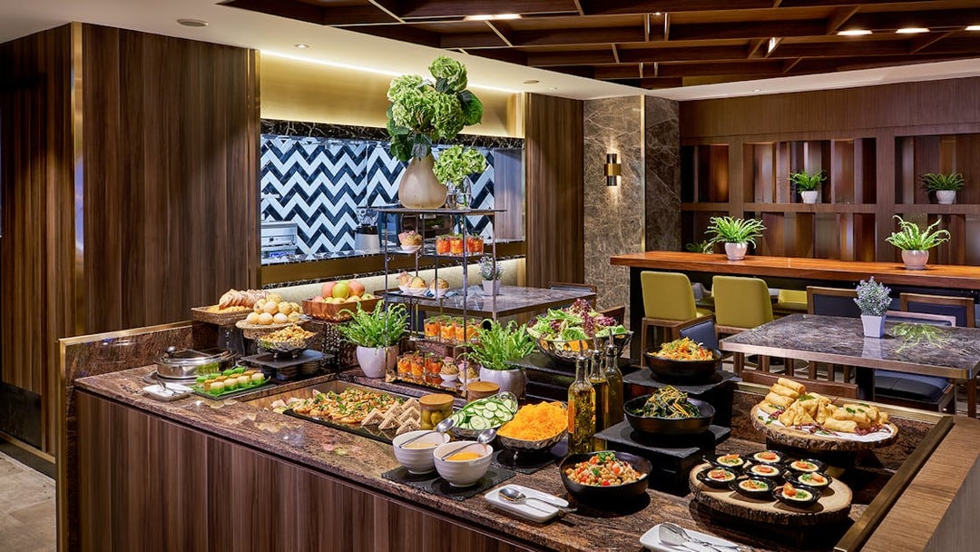 Buffet spread at Plaza Premium Lounge, Penang International Airport, featuring salads, pastries, and beverages.