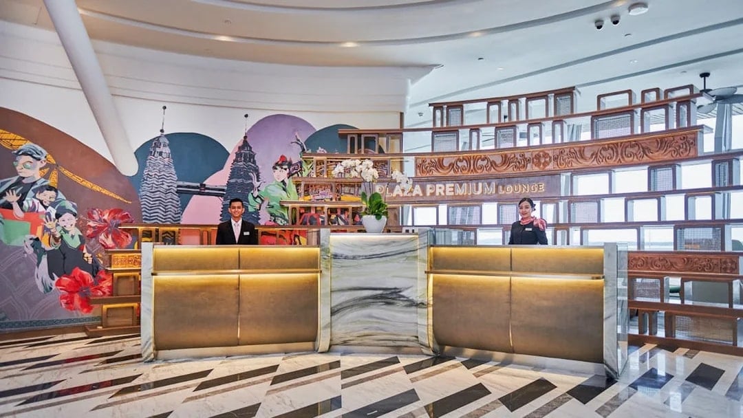 Reception area of Plaza Premium Lounge at KLIA Terminal 1 with staff and mural.