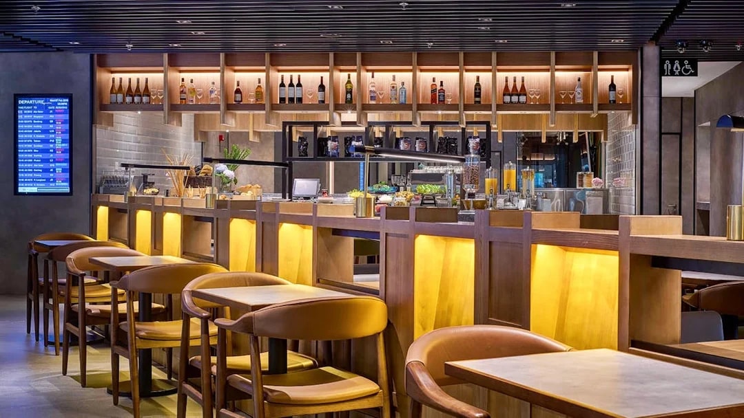 Plaza Premium Lounge seating and bar area at KLIA Terminal 2 with departure board.