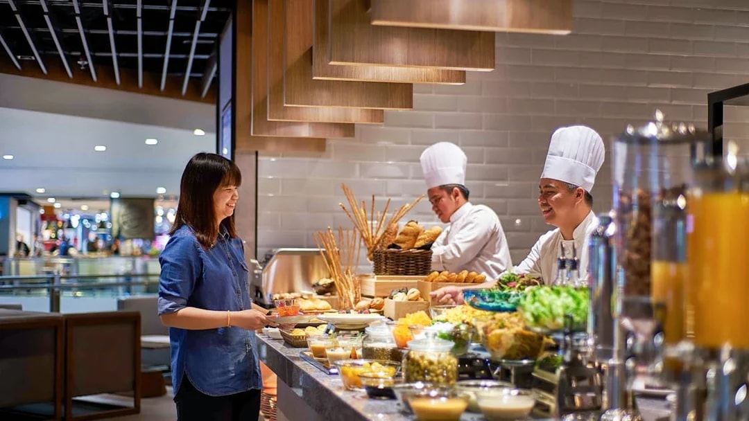 Guest enjoying buffet at Plaza Premium Lounge, KLIA Terminal 2, with chefs preparing food.
