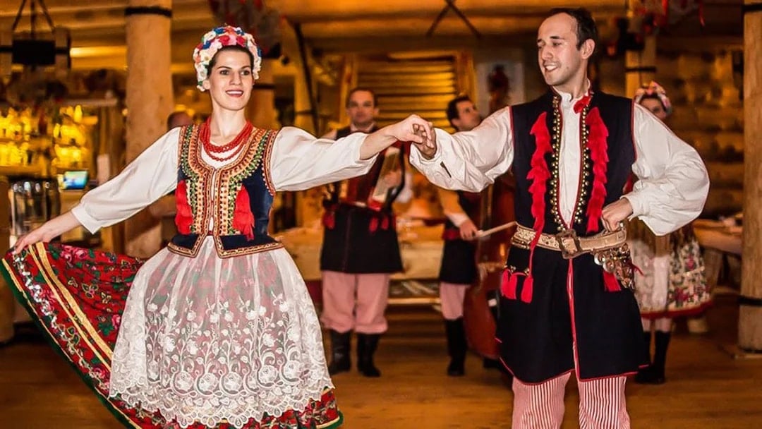 Dancers in traditional Polish costumes performing at a folk show with dinner.