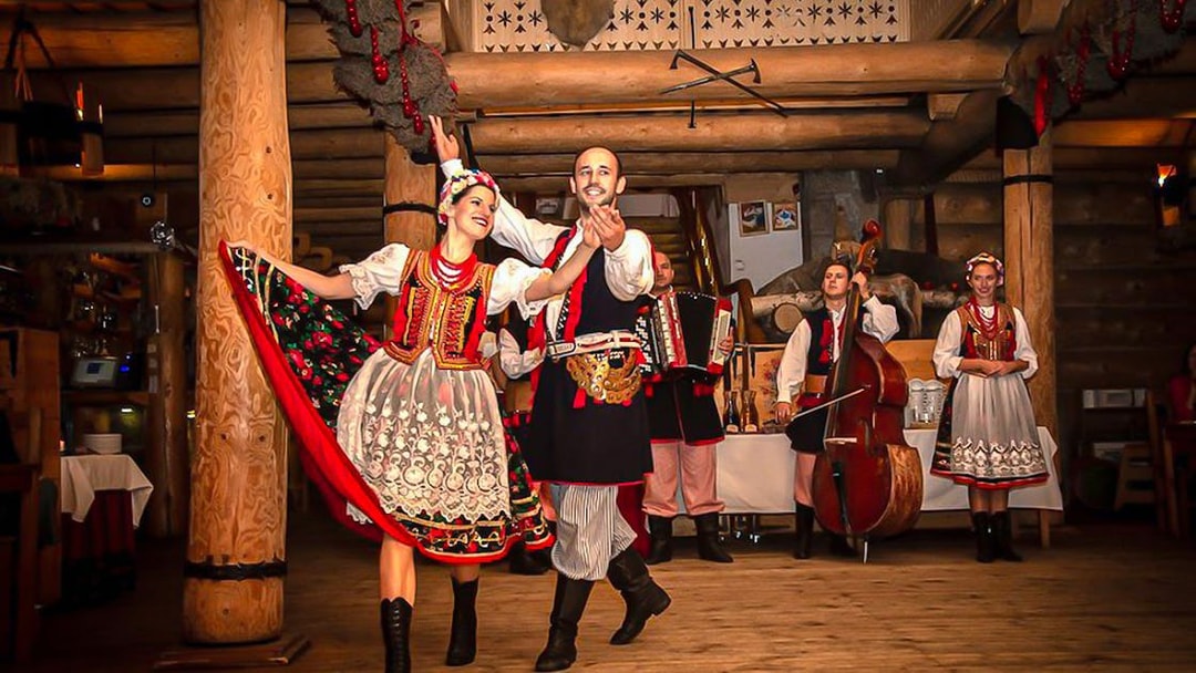 Polish folk dancers performing with musicians during an all-you-can-eat dinner show.