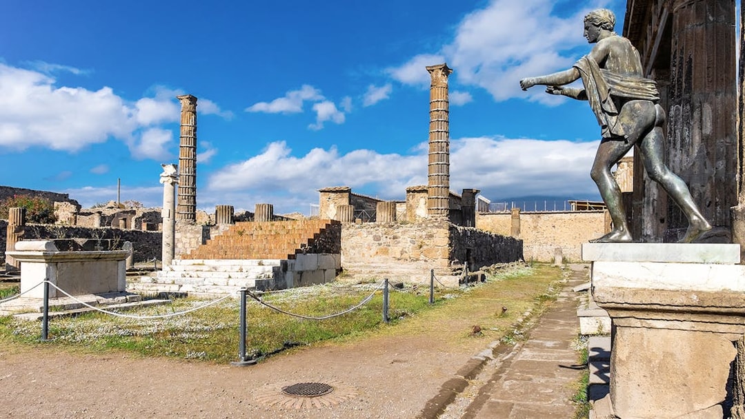 Temple of Apollo ruins with statue and columns in Pompeii, Italy.