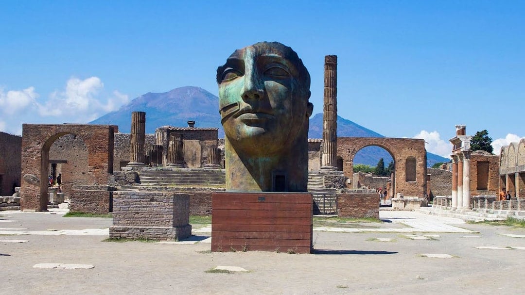 Ancient Pompeii ruins with large sculpture and Mount Vesuvius in background, Naples, Italy.