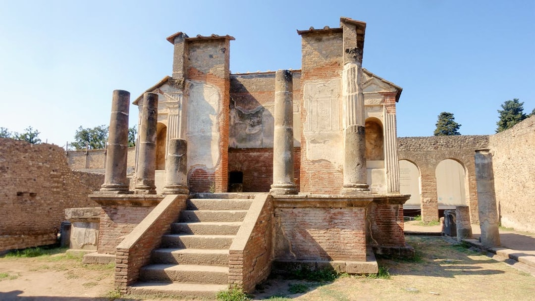 Ancient ruins of a temple in Pompeii with stone columns and steps.