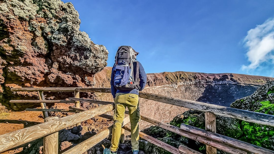 Hiker on Mount Vesuvius trail with view of crater, Italy.