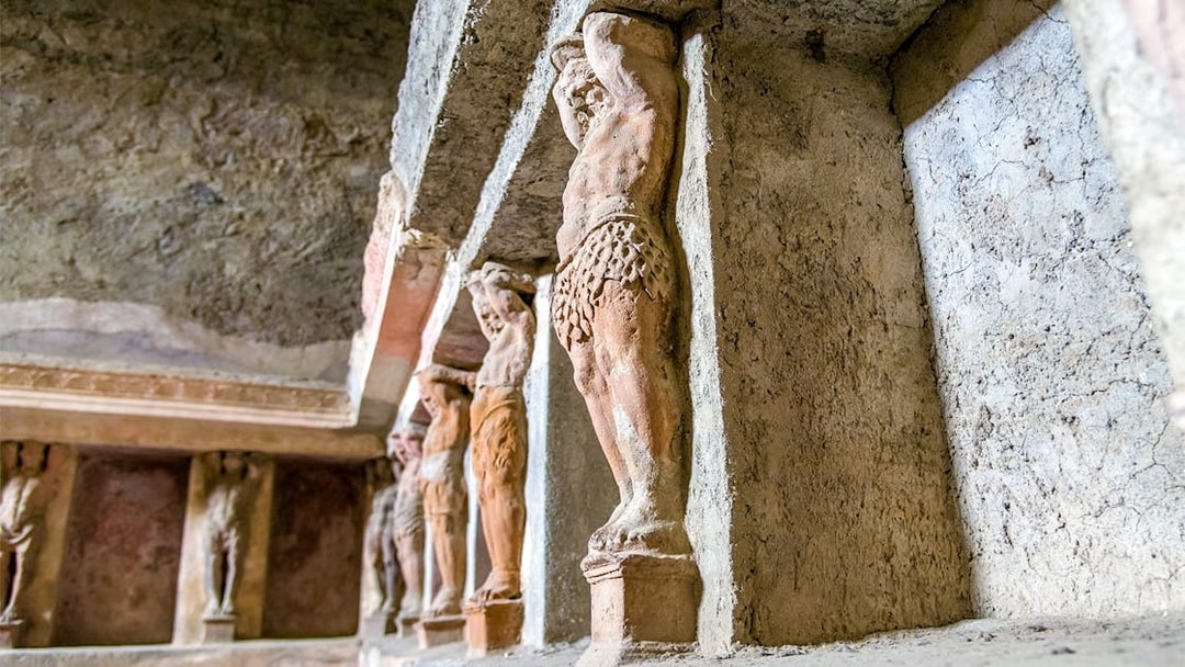 Ancient statues in the Pompeii Baths, Italy, depicting figures supporting a structure.