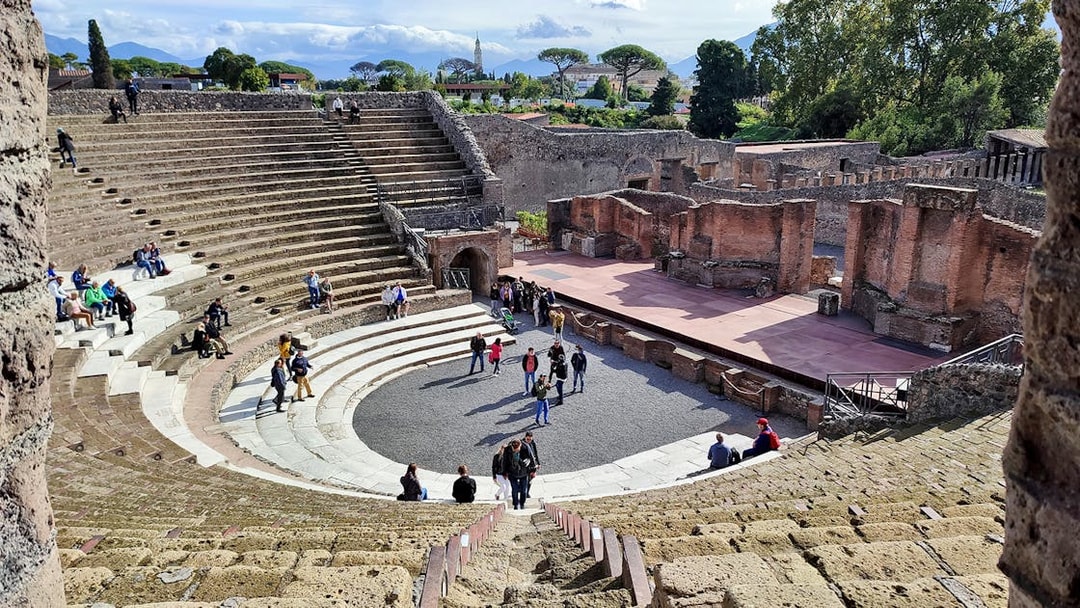 Ancient amphitheater in Pompeii with tourists exploring the site.