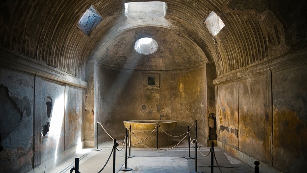 Ancient room in Pompeii with sunlight through ceiling, part of guided tour.