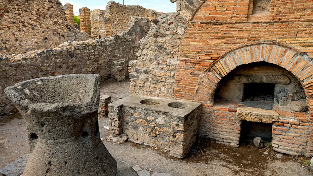 Ancient ruins of a bakery in Pompeii with stone oven and millstone.