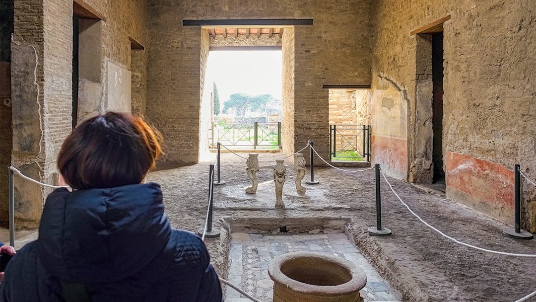 Tourists exploring the ancient Samnite House interior in Pompeii, Italy.