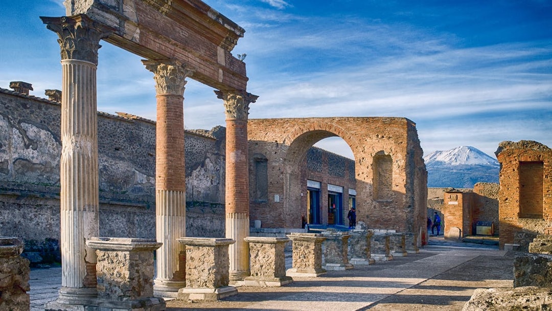 Ancient ruins of Pompeii with Mount Vesuvius in the background.