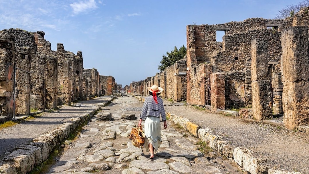 Person walking on cobbled streets of ancient Pompeii ruins, Italy.