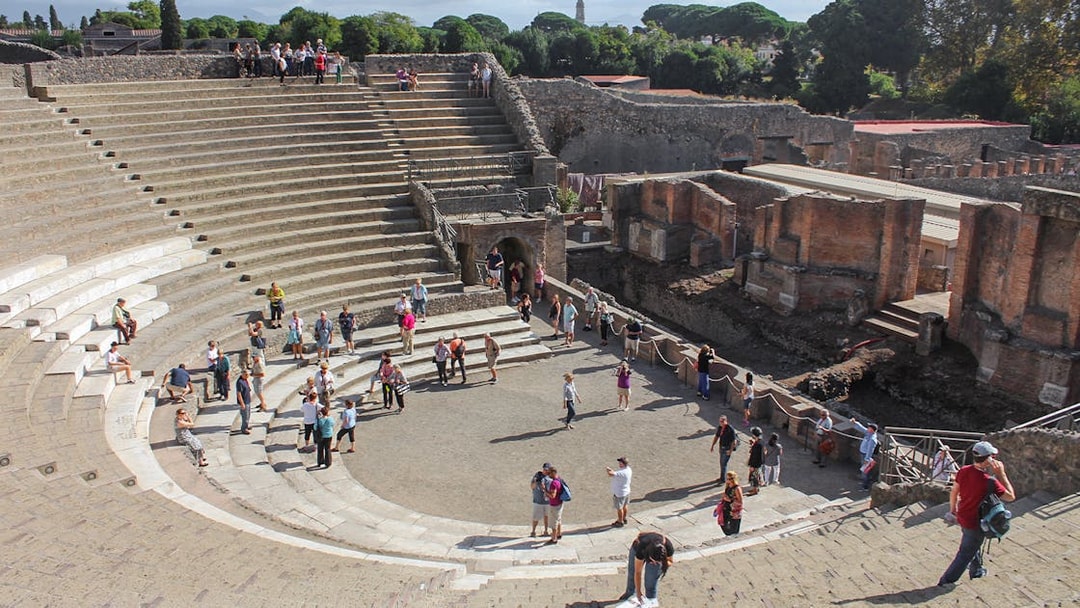Tour group with guide at Pompeii amphitheatre, Italy.