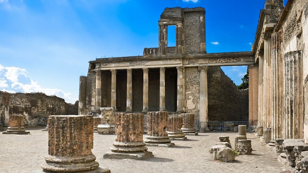 Pompeii Basilica ruins with ancient columns under a clear blue sky.