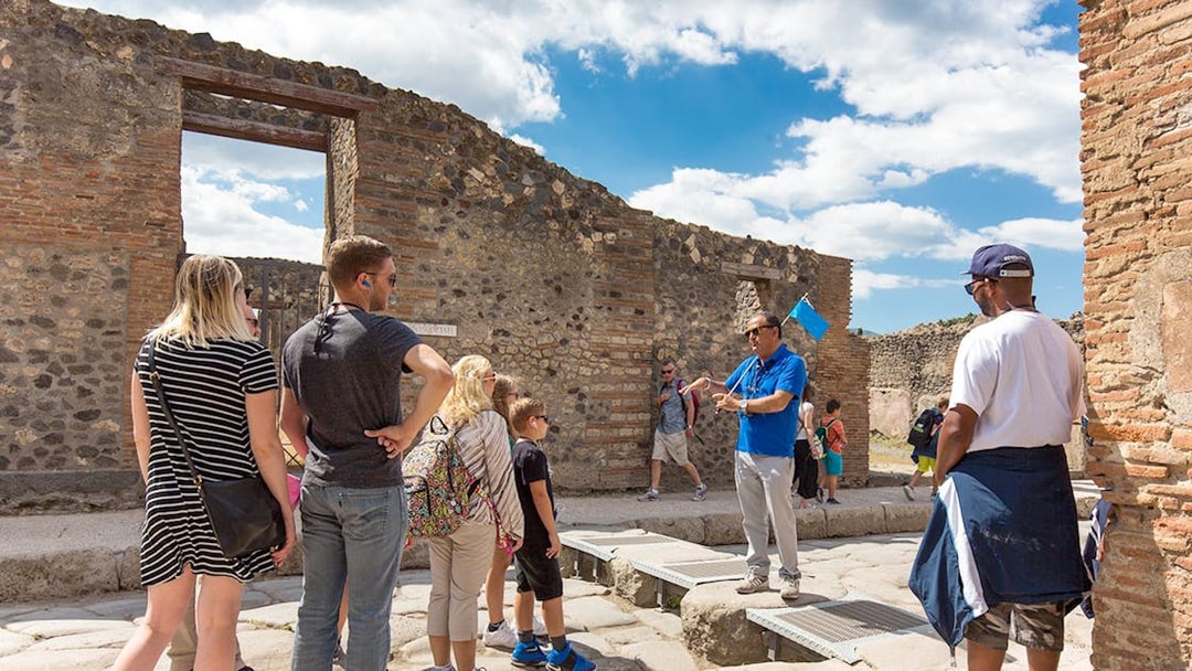 Visitors listening to a tour guide in Pompeii ruins, Italy.