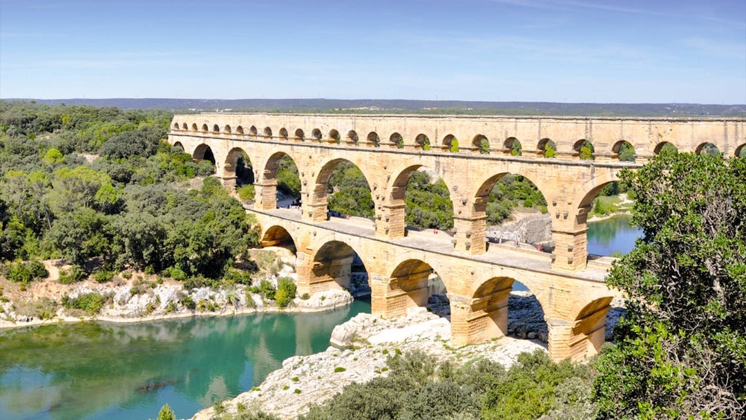 Pont du Gard aqueduct spanning a river in a lush landscape, France.