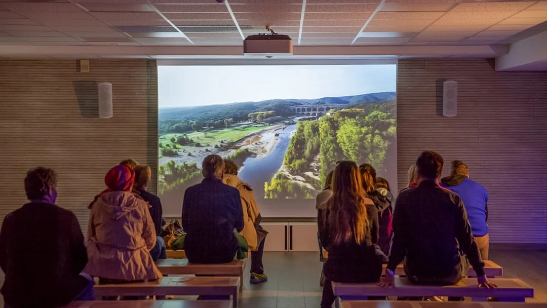 Visitors watching a Pont du Gard documentary in a museum cinema.