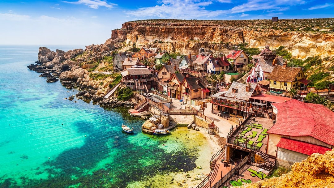Popeye Village Malta with colorful wooden houses by the sea.