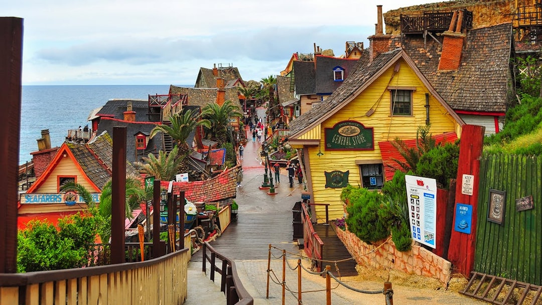 Street view of colorful wooden buildings in Popeye Village, Malta, near the sea.