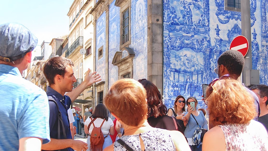 Tour group exploring azulejo tiles on a historic building in Porto.