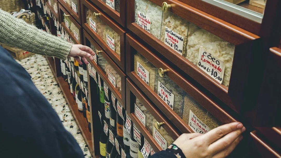 Hands selecting items from a shelf in a Porto food shop during a wine tour.