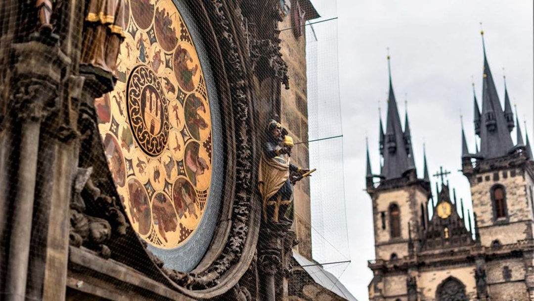 Astronomical Clock in Prague with Gothic church spires in the background.
