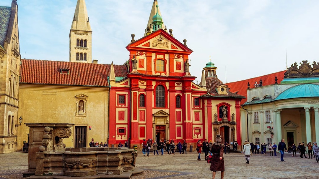 St. George's Basilica at Prague Castle with tourists in the courtyard.
