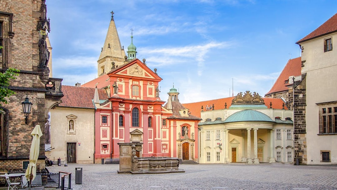 Basilica of St George exterior with red facade and courtyard in Prague.