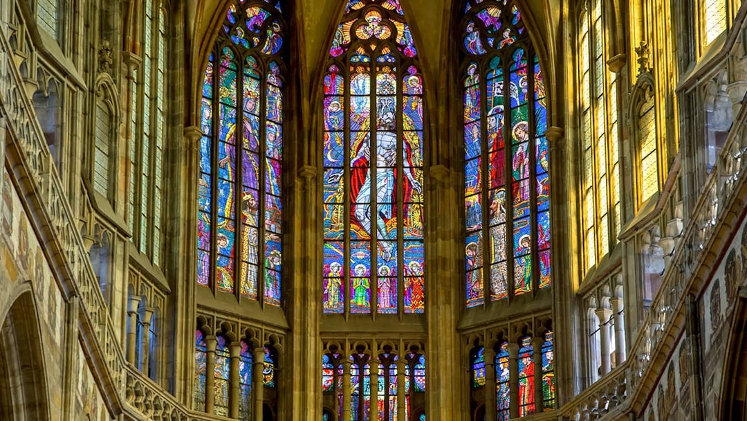 Stained glass windows inside St Vitus Cathedral, Prague, depicting religious scenes.