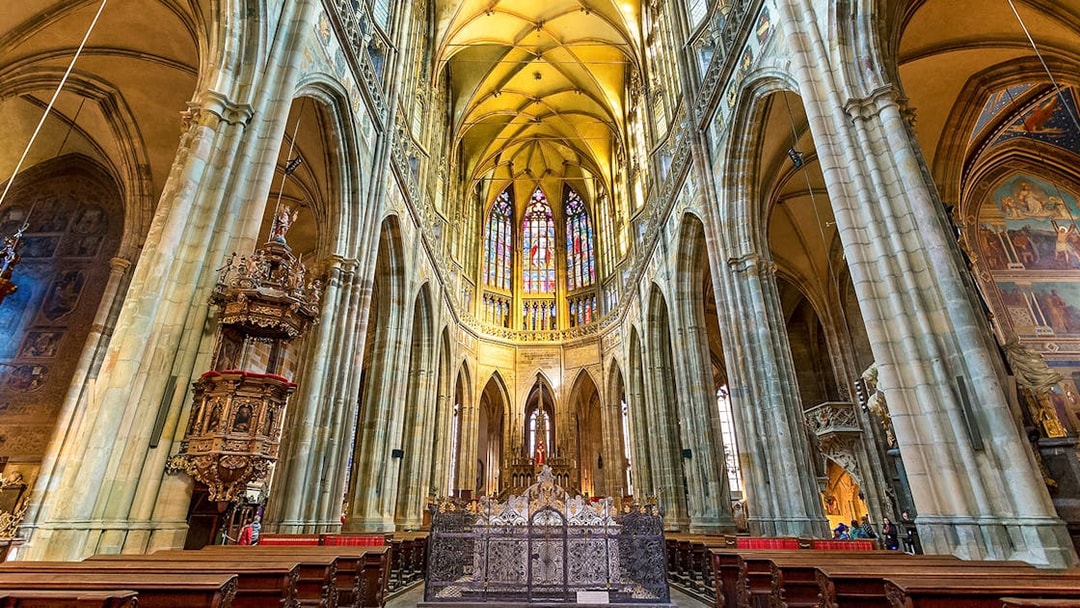 Gothic interior of Saint Vitus Cathedral with stained glass windows and vaulted ceilings.