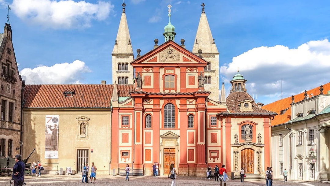 Basilica of St George exterior with tourists in Prague courtyard.