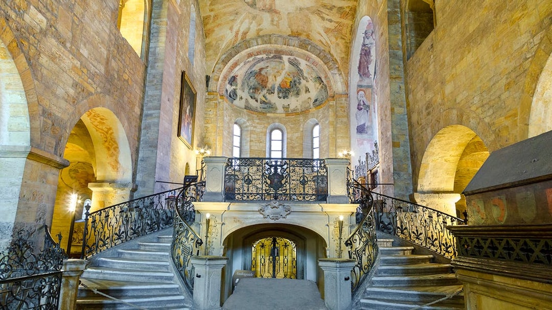 Basilica of St George interior with ornate staircase and frescoed ceiling.