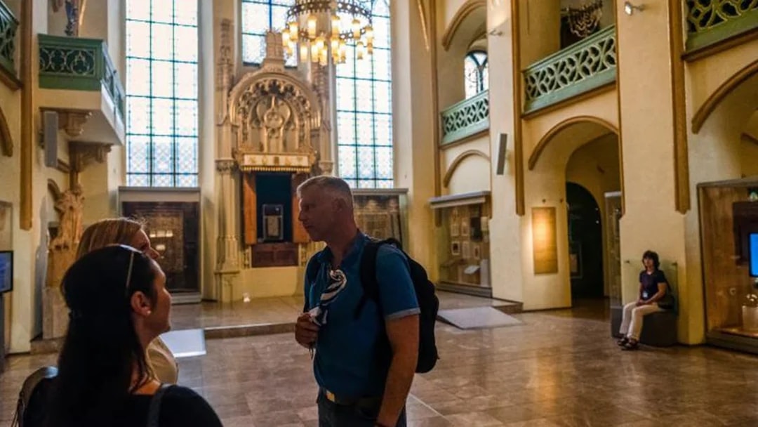 Tour group inside a historic synagogue in Prague's Jewish Quarter.